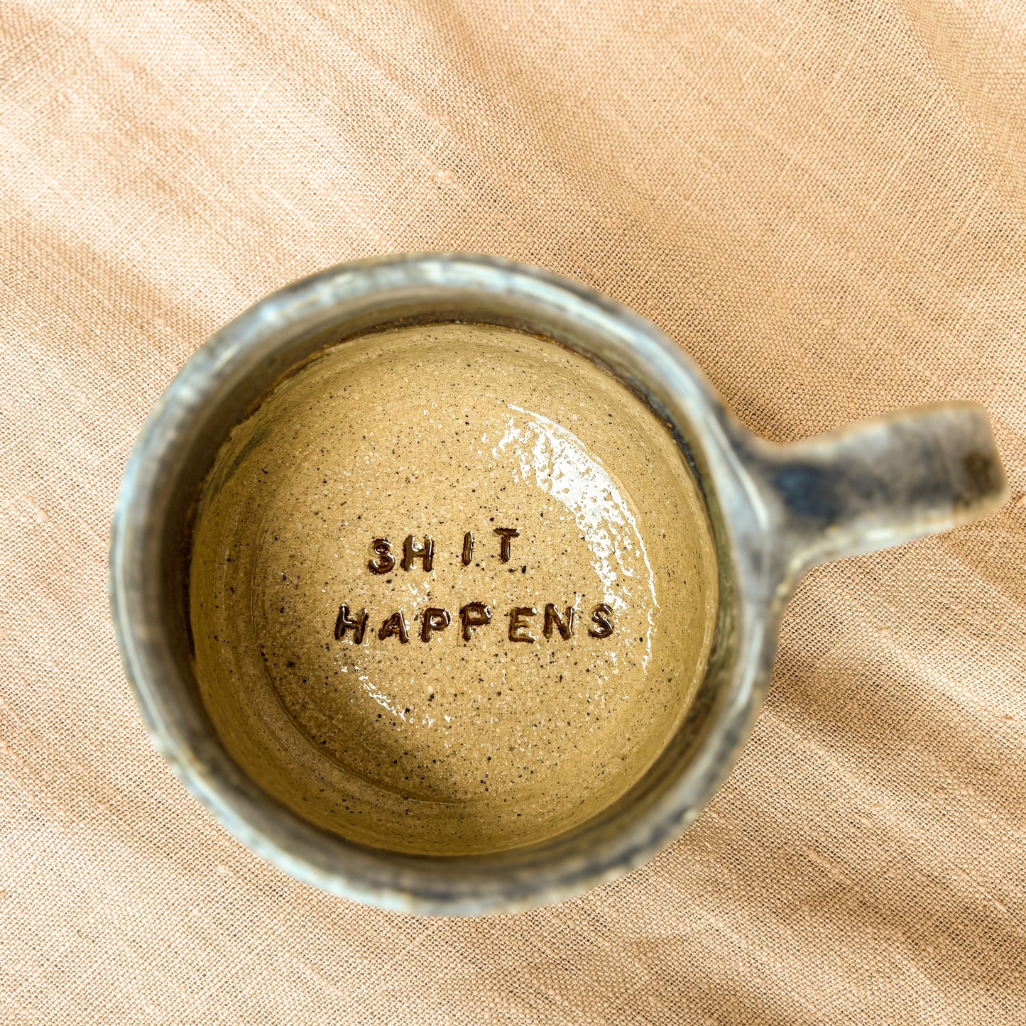 Handmade mug, dark blue, shit happens, overhead shot